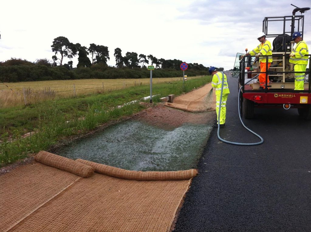 Fully biodegradeable HydraCX being sprayed onto the green drainage channel to aid erosion control.